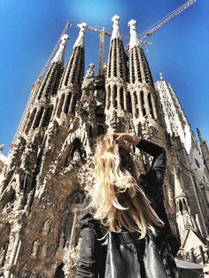 a woman standing in front of a very tall building that has spires on it