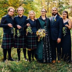 a group of people standing next to each other in a field with trees behind them