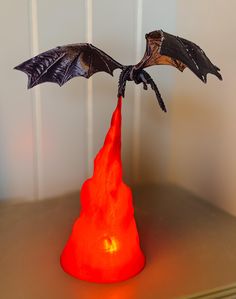 a dragon sculpture sitting on top of a red lava lamp in front of a white wall