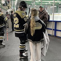 two hockey players are talking to each other in the locker room with their coach and assistant