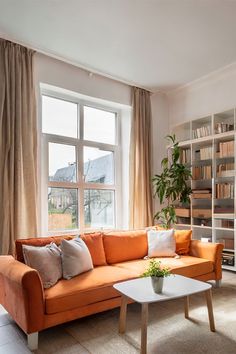 a living room with orange couches and bookshelves next to a large window