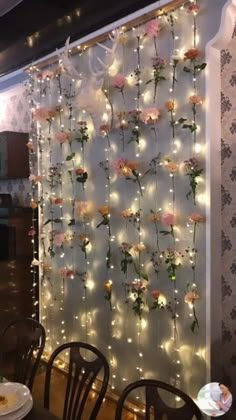 the flowers are hanging on the wall behind the chairs in the dining room, with fairy lights strung all over it