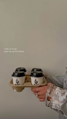 a woman holding two coffee cups on a tray