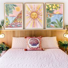 three paintings hang above a bed with pink bedspread and pillows on the headboard