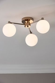 a ceiling light with three white globes hanging from it's center point in a living room