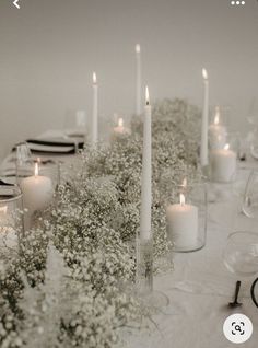 a table topped with lots of white flowers and candles