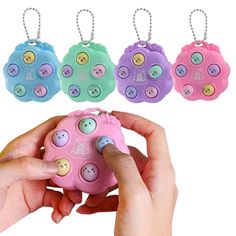 a hand holding a pink, blue, and green button keychain with four different buttons