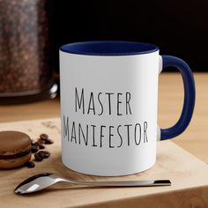 a blue and white coffee mug sitting on top of a wooden table next to a cookie