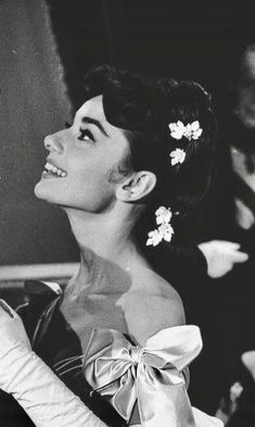 a black and white photo of a woman with flowers in her hair wearing a dress