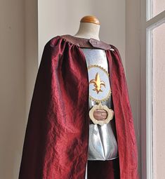 a mannequin dressed in a red cape and silver armor with a gold star on it