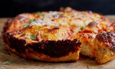 a cheesy pizza is cut in half on a cutting board