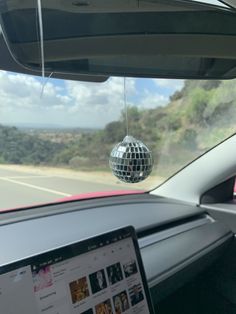 a disco ball hanging from the ceiling of a car's dashboard, in front of a laptop computer