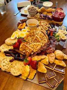 a wooden table topped with waffles, fruit and other foods on top of it