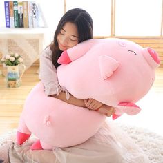 a woman holding a large pink pig stuffed animal