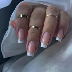 a woman's hands with french manies and gold rings on their fingers,