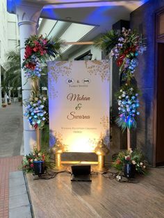 an outdoor wedding ceremony setup with flowers and greenery on the front steps, lit up by blue lights