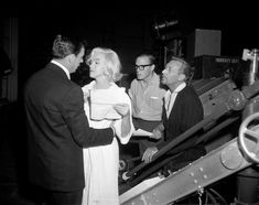 black and white photograph of people standing in front of a conveyor belt at night