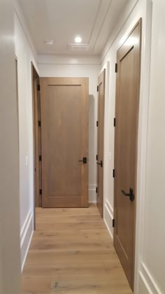 an empty hallway with wooden doors and hard wood flooring