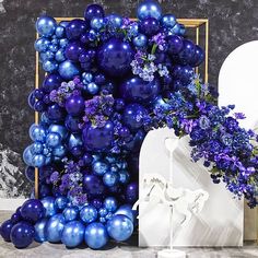 purple and blue balloons are on display next to a white vase with flowers in it