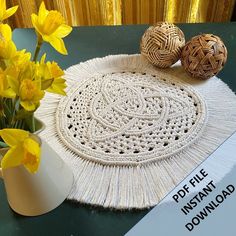 some yellow flowers are sitting on a table next to a doily and vase with daffodils