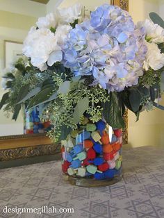 a vase filled with blue and white flowers on top of a table next to a mirror