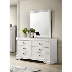 a white dresser with a mirror on top of it next to a rug and potted plant