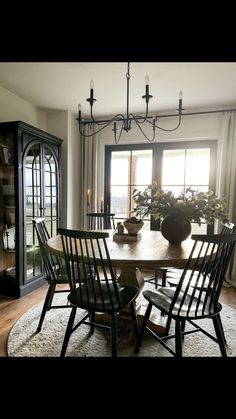 the dining room table is surrounded by chairs and vases with plants on them in front of an open window