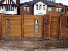 a wooden fence is in front of a brick house with two doors and windows on each side