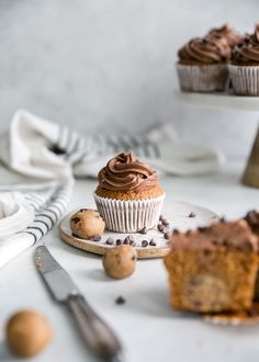 two chocolate cupcakes sitting on top of a white plate next to a knife