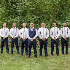 a group of men standing next to each other on top of a lush green field