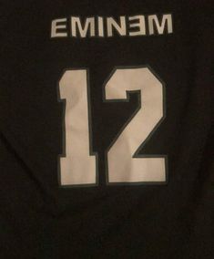 the back of a black jersey with white numbers on it, which reads emin3m