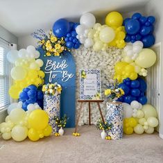 balloons and flowers decorate the backdrop for a bridal party in blue, yellow and white