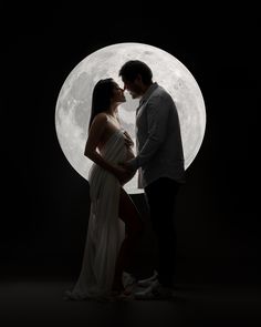 a man and woman standing in front of a full moon