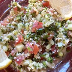 a red plate topped with salad and lemon wedges