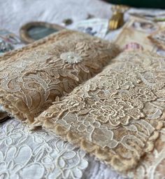 an open book with lace on it sitting on top of a white table cloth next to other items