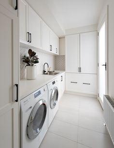 a washer and dryer in a white laundry room with cupboards on either side