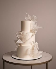 a three tiered white wedding cake sitting on top of a table