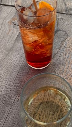 a glass filled with liquid next to an orange slice on top of a wooden table