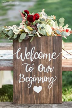 a wooden sign that says welcome to our beginning with flowers and greenery on top