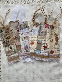 four tags are hanging from twine with lace on the bottom one is filled with pictures and words