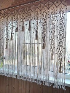 the curtains are hanging on the window sill in front of the windowsill, which is decorated with bells and tassels