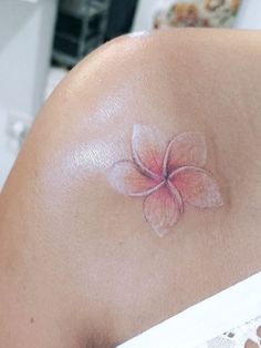 a pink flower on the back of a woman's shoulder