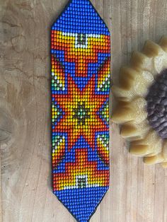 a beaded tie next to a cupcake on a wooden table with a flower