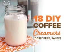 a glass jar filled with creamer sitting on top of a table next to a cup