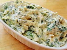 a casserole dish with spinach and chicken in it on a wooden table