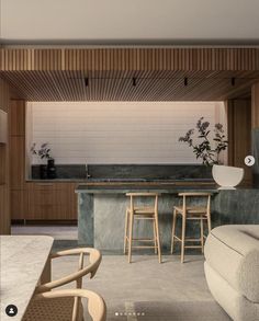 an open kitchen and living room area with bar stools in the center, wood paneling on the walls