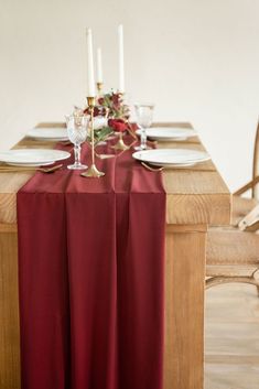 the table is set with white plates and silverware, red cloth draped over it