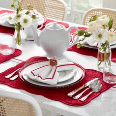 the table is set with white and red place settings