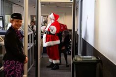 a man dressed as santa clause standing next to a woman in an office cubicle