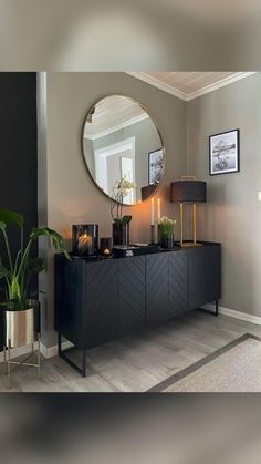 a living room with a large round mirror on the wall next to a black dresser